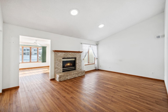 unfurnished living room featuring lofted ceiling, a fireplace, plenty of natural light, and wood finished floors