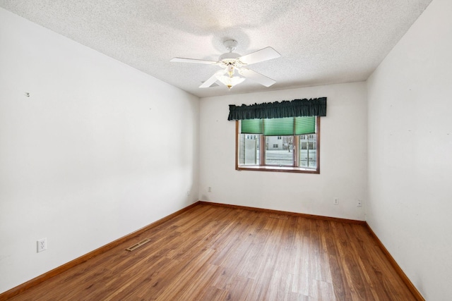 unfurnished room with baseboards, ceiling fan, visible vents, and wood finished floors