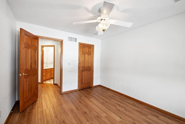 unfurnished bedroom featuring a textured ceiling, a ceiling fan, visible vents, baseboards, and light wood finished floors