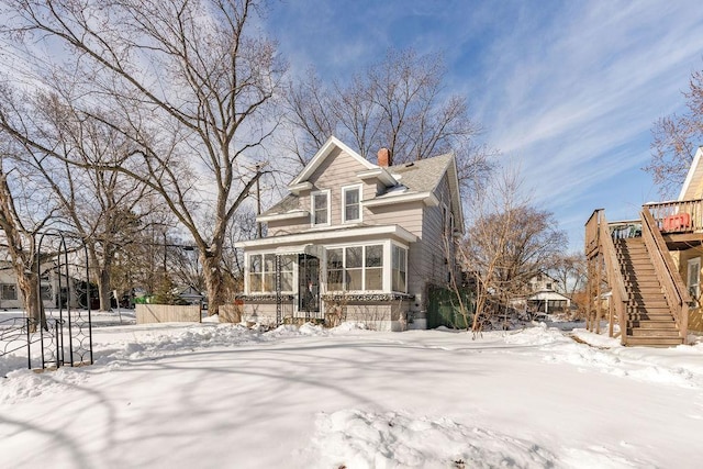 view of front of home featuring stairway, a chimney, and a sunroom