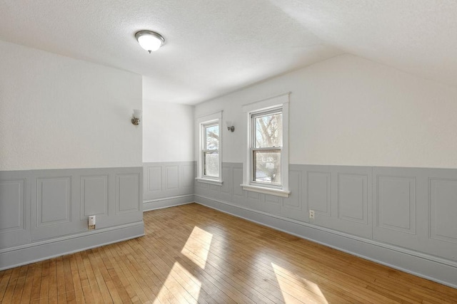 interior space featuring a textured ceiling, vaulted ceiling, and hardwood / wood-style floors