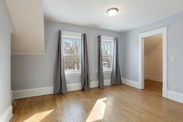 unfurnished room featuring light wood-style flooring, baseboards, and a textured ceiling