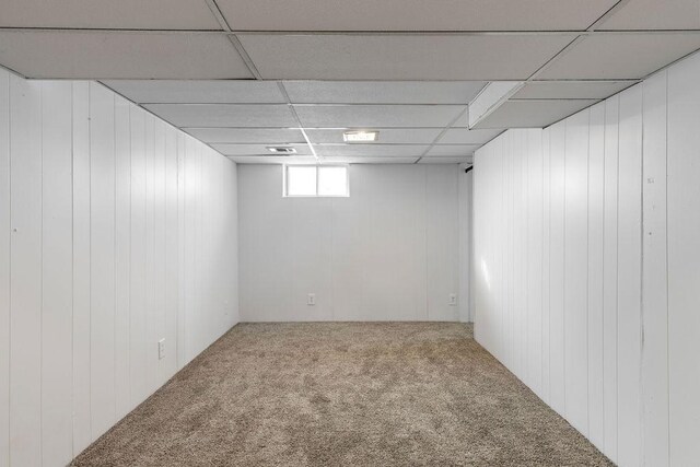 below grade area with a paneled ceiling and carpet flooring