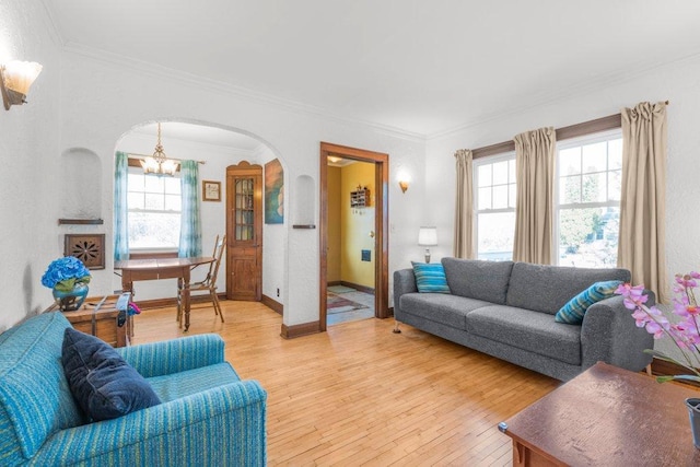 living area featuring arched walkways, plenty of natural light, light wood-style flooring, and ornamental molding