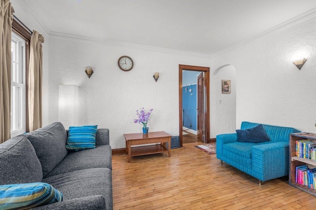 living area featuring arched walkways, light wood-type flooring, crown molding, and a textured wall