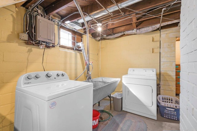 washroom featuring electric panel, laundry area, washer and dryer, and a sink