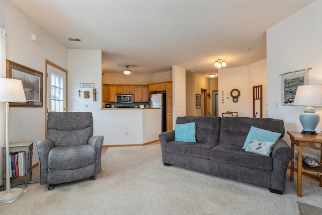 living area featuring baseboards, light carpet, a textured ceiling, and visible vents