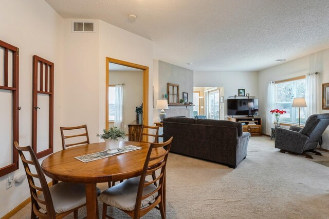 dining area with visible vents, light colored carpet, a textured ceiling, and baseboards