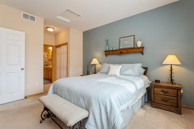 carpeted bedroom with baseboards, visible vents, ensuite bath, a closet, and a textured ceiling