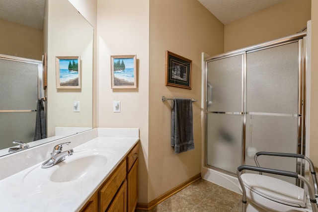 bathroom with baseboards, toilet, vanity, a shower with shower door, and a textured ceiling