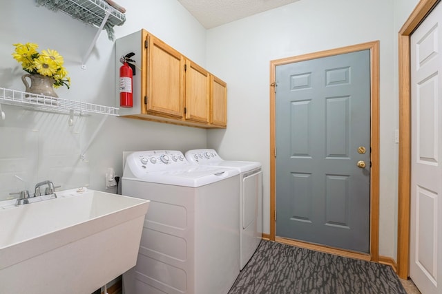 clothes washing area with a sink, baseboards, cabinet space, and washing machine and dryer