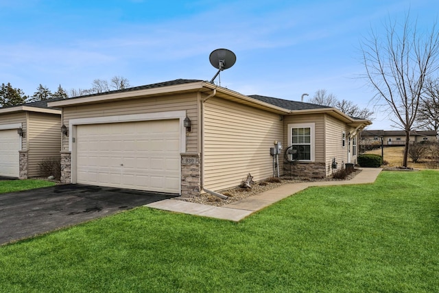 exterior space featuring a front lawn, an attached garage, stone siding, and driveway