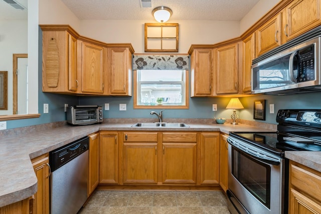 kitchen featuring visible vents, a toaster, stainless steel appliances, a textured ceiling, and a sink