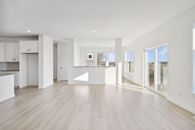 unfurnished living room featuring baseboards, light wood-style flooring, and recessed lighting