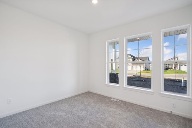 spare room featuring visible vents, carpet, a wealth of natural light, and baseboards