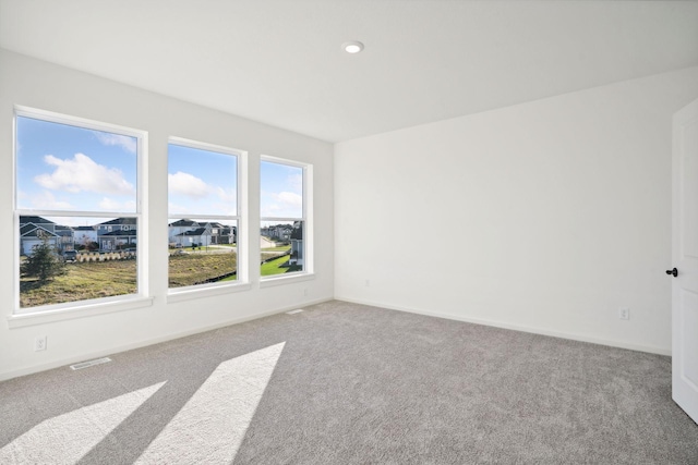 spare room with baseboards, a residential view, visible vents, and light colored carpet