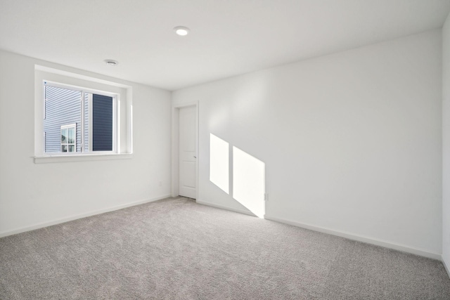 empty room featuring light carpet and baseboards