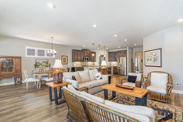 living room with baseboards, recessed lighting, light wood-style flooring, an inviting chandelier, and arched walkways