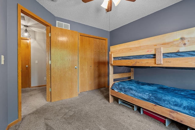 carpeted bedroom featuring visible vents, baseboards, ceiling fan, a closet, and a textured ceiling