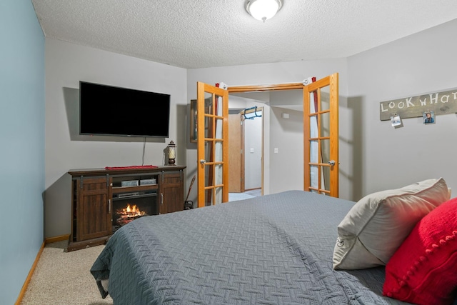 carpeted bedroom with baseboards, a warm lit fireplace, and a textured ceiling