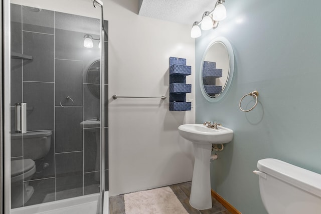 bathroom with a stall shower, toilet, baseboards, and wood finished floors