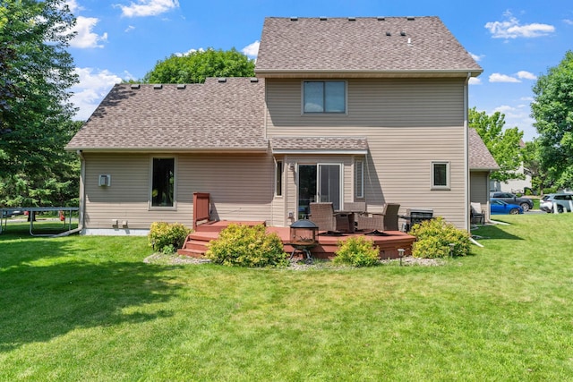 rear view of house featuring a wooden deck, a yard, and roof with shingles