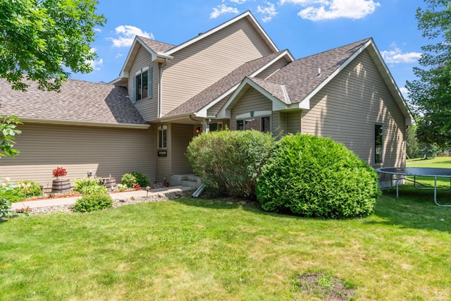 view of front of house featuring a trampoline, roof with shingles, and a front lawn