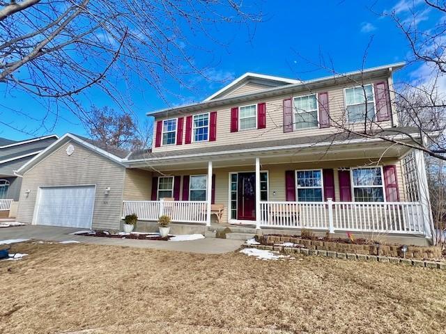 view of front of home featuring an attached garage, covered porch, and driveway