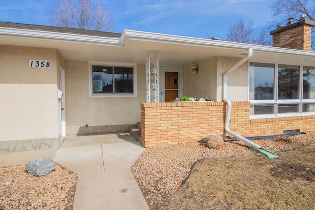 property entrance featuring crawl space, brick siding, and stucco siding