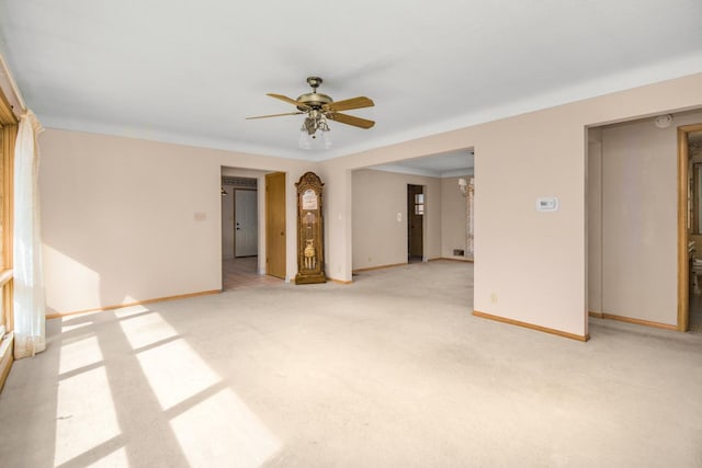 carpeted empty room featuring baseboards and ceiling fan