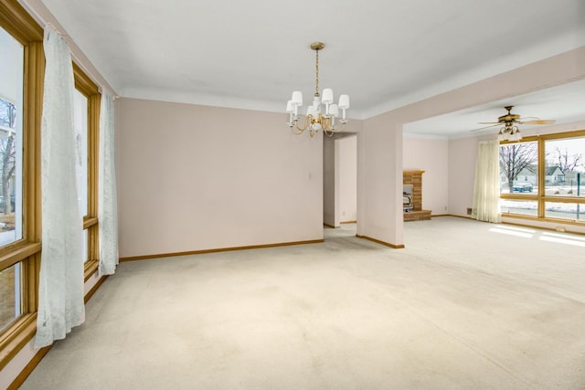 empty room featuring a fireplace with raised hearth, light colored carpet, baseboards, and an inviting chandelier