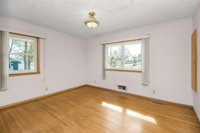 unfurnished room featuring visible vents, plenty of natural light, light wood-style floors, and baseboards