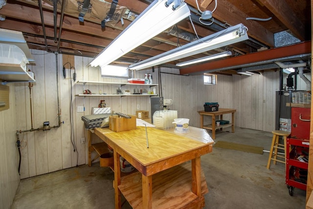 below grade area with water heater, a workshop area, and wood walls