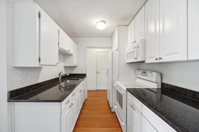 kitchen with white appliances, light wood-style flooring, a sink, white cabinets, and a textured ceiling