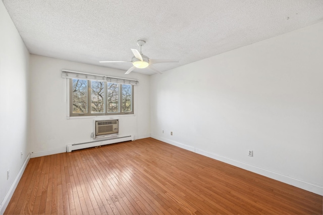 spare room with light wood-type flooring, an AC wall unit, a baseboard radiator, baseboards, and ceiling fan