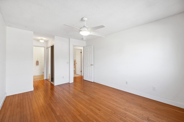 spare room with a ceiling fan, baseboards, light wood-type flooring, and a textured ceiling