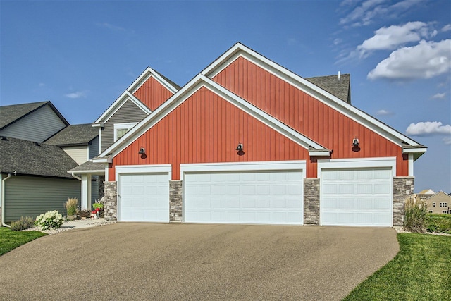 craftsman-style home with a garage, driveway, and stone siding