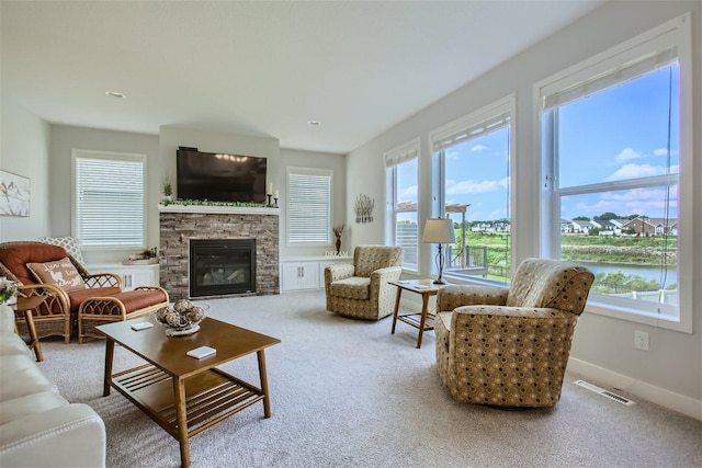 living area with a healthy amount of sunlight, visible vents, a stone fireplace, and baseboards