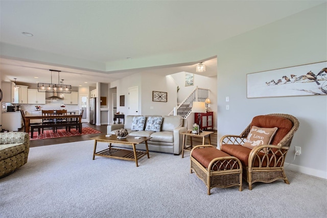 carpeted living area featuring stairs and baseboards