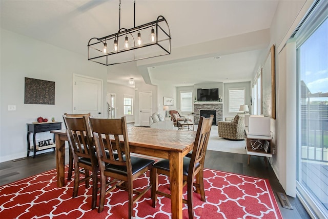 dining area with dark wood-type flooring, visible vents, and a fireplace