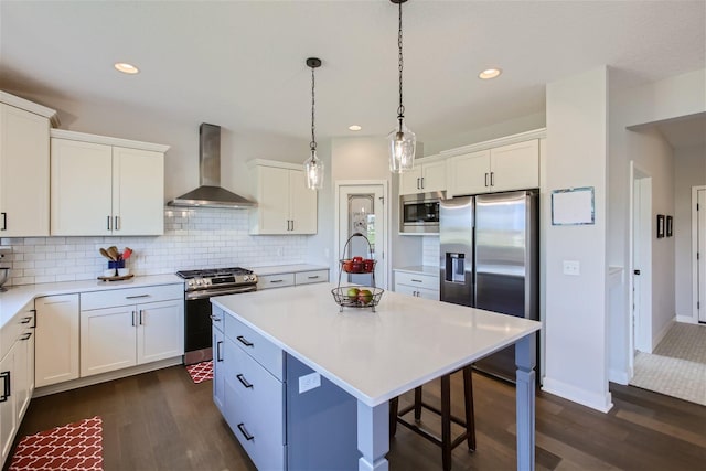 kitchen with stainless steel appliances, a kitchen island, white cabinetry, light countertops, and wall chimney exhaust hood