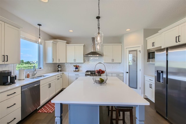 kitchen with a breakfast bar, stainless steel appliances, light countertops, backsplash, and wall chimney range hood