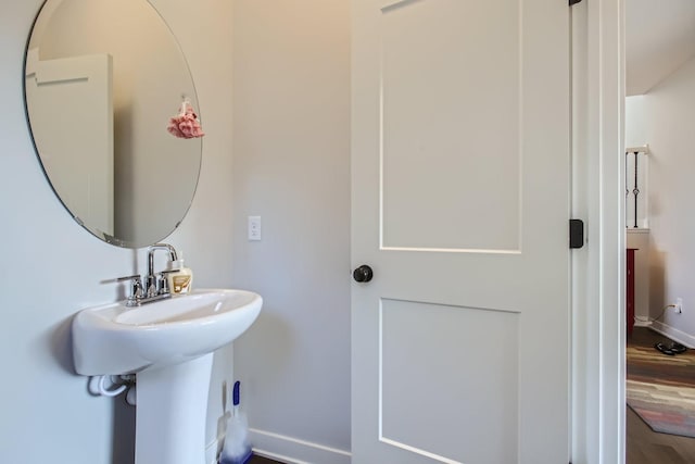 bathroom with a sink, wood finished floors, and baseboards