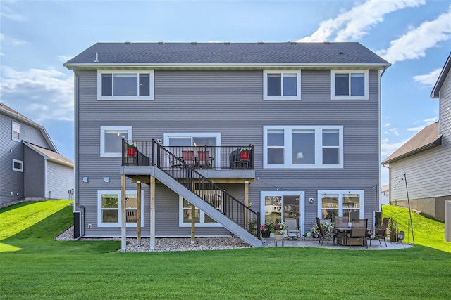 back of house with a deck, a patio, a shingled roof, stairs, and a lawn