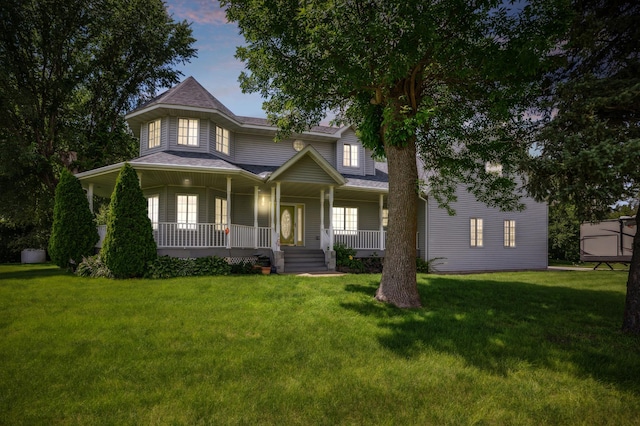 victorian house with covered porch, roof with shingles, and a front yard