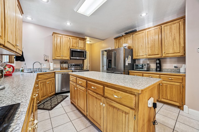 kitchen featuring stainless steel appliances, light tile patterned flooring, a sink, and a kitchen island