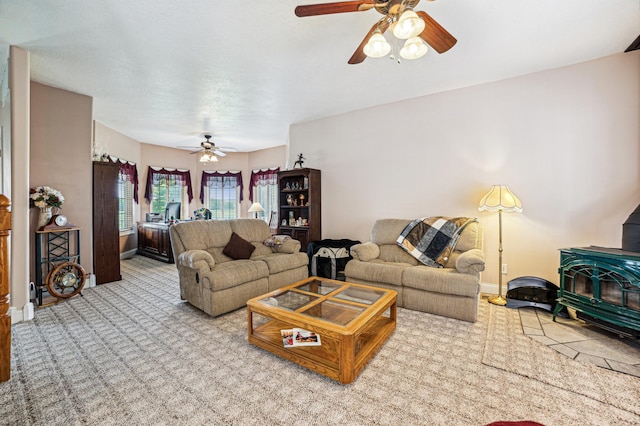 living area with ceiling fan, carpet flooring, a wood stove, and baseboards