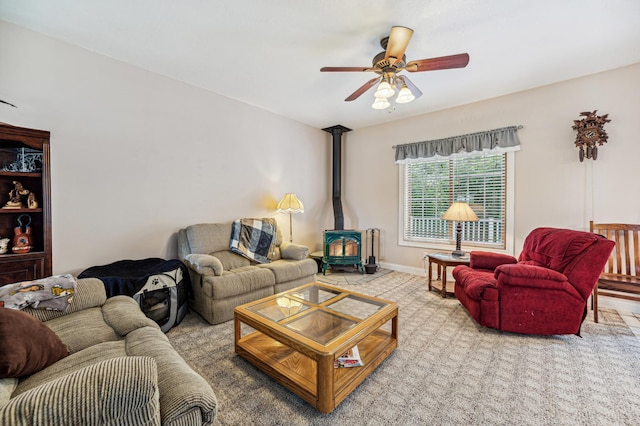 living room featuring a ceiling fan, a wood stove, and baseboards