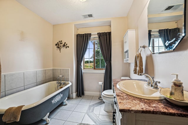 full bath with toilet, a freestanding tub, visible vents, and tile patterned floors