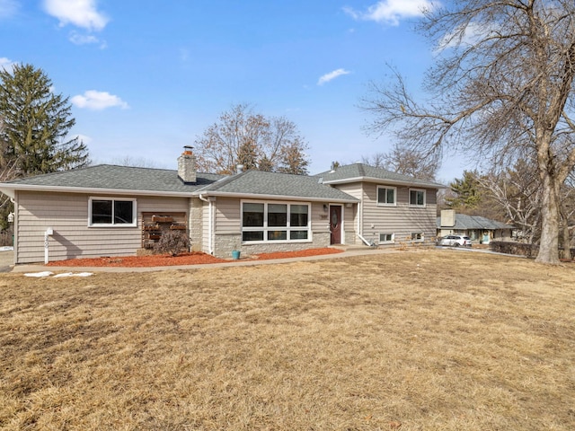 rear view of house featuring a lawn, a chimney, and a shingled roof